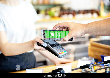 Waitress holding card reader POS pour l'homme de payer par téléphone intelligent Banque D'Images