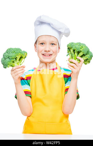 Portrait psychologique d'un garçon en cook hat et un tablier avec brocoli isolé sur fond blanc Banque D'Images