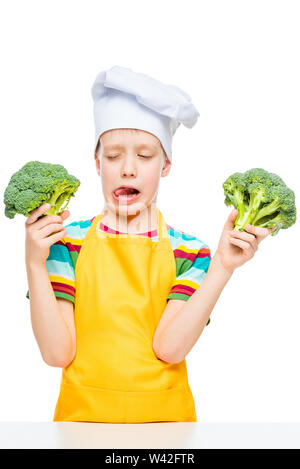 Portrait vertical d'un garçon qui n'aime pas le brocoli dans un chapeau de cuisinier sur un fond blanc Banque D'Images