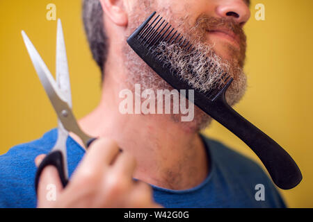 Homme barbu, ciseaux et brosse sur un fond jaune. Les gens, le mode de vie et de beauté concept Banque D'Images