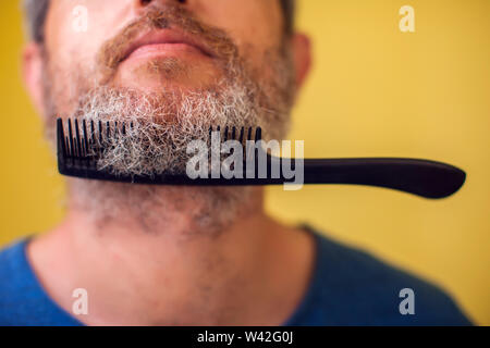 Homme avec une barbe et de brosse sur un fond jaune. Les gens, le mode de vie et de beauté concept Banque D'Images