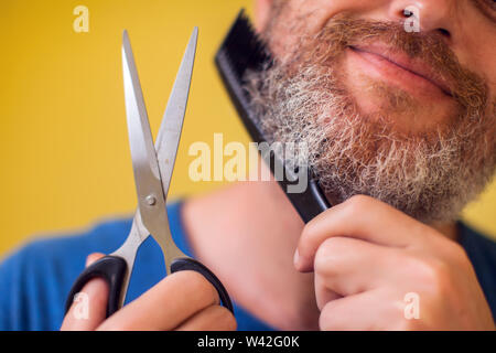 Homme barbu, ciseaux et brosse sur un fond jaune. Les gens, le mode de vie et de beauté concept Banque D'Images