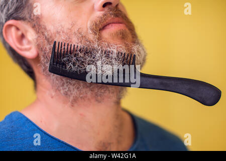 Homme avec une barbe et de brosse sur un fond jaune. Les gens, le mode de vie et de beauté concept Banque D'Images