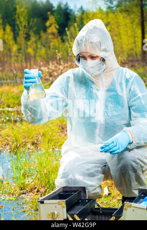 Avec des outils et écologiste en flacons échantillons d'eau d'un lac de la forêt pour la recherche sur les bactéries dangereuses Banque D'Images