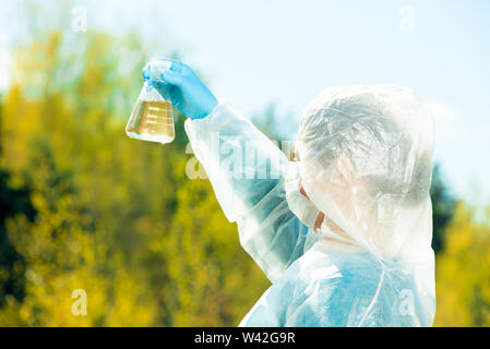 Détermine les propriétés d'écologiste visuellement l'eau, l'échantillon est prélevé dans une fiole de l'étang Banque D'Images