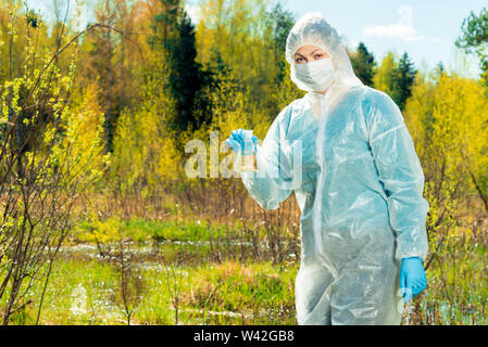 Un écologiste spécialiste avec une fiole d'eau d'un étang de la forêt mène des recherches Banque D'Images