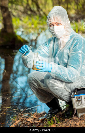 Écologiste et avec les tubes à essai et des analyses des flacons d'eau dans un étang de la forêt Banque D'Images