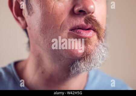 Portrait d'un homme avec la moitié de la barbe et cheveux sur fond brun Banque D'Images