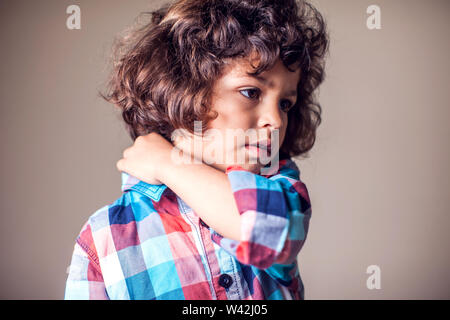 Un garçon tenant son cou douloureux. Les enfants, les soins de santé, medicine concept Banque D'Images