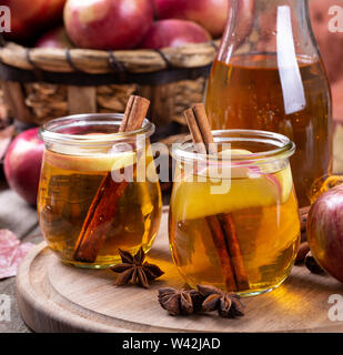 Deux verres de cidre de tranches de pomme et de cannelle sur un plateau en bois avec panier de pommes en arrière-plan Banque D'Images