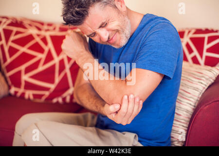 L'homme sent une forte douleur du coude à la maison. Personnes, santé et médecine concept Banque D'Images