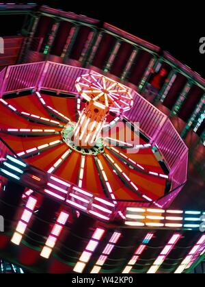 Gros plan d'un carrousel tournant dans un parc d'attractions pendant un carnaval la nuit Banque D'Images