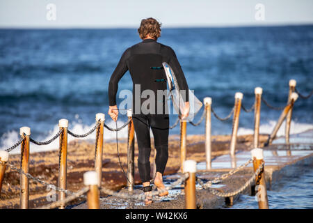 Sydney Surfer, man carrying his surfboard prêt pour un après-midi de surf sur les plages du nord de Sydney, Australie Banque D'Images