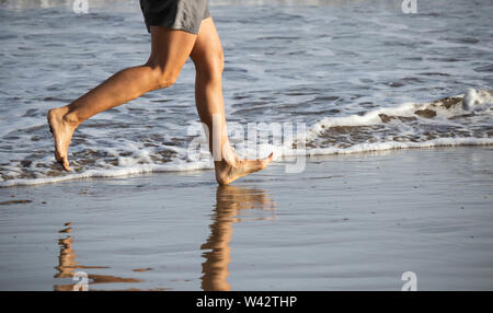 Femme mature en marche pieds nus sur la plage. Banque D'Images