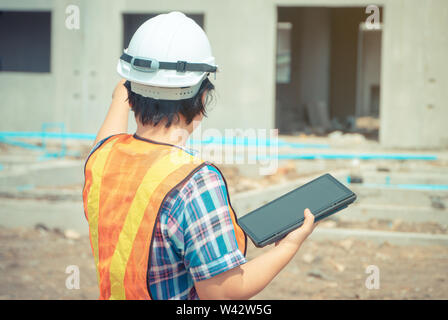 Les femmes asiatiques engineering est titulaire d'une tablette pour une utilisation dans l'inspection des chantiers de construction pour plus de précision et en conformité avec le plan. Concept de l'égalité de Banque D'Images