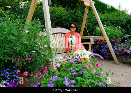 Un joli couple assis sur un banc en bois, looking at camera, UK - John Gollop Banque D'Images
