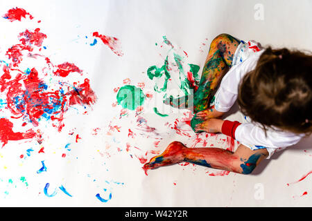 Bébé Enfant la peinture au doigt sur un livre blanc sur le plancher Banque D'Images