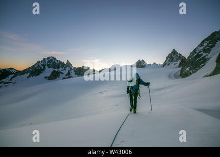 Un alpiniste utilise un pôle trekking sur terrain glaciaire avant l'aube, Banque D'Images