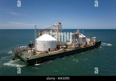 Exploitation minière, gestion et transport des sables bitumineux en titane. Barge arrivant à la jetée pour charger avec du minéral avant le transfert à OGV à l'horizon Banque D'Images