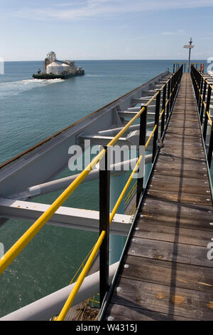 Exploitation minière, gestion et transport des sables bitumineux en titane. Barge quittant le port pour décharger le produit dans l'OGV en mer et montrant l'infrastructure de la jetée . Banque D'Images