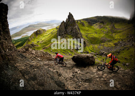 Deux cyclistes de montagne équitation à travers les spectaculaires pics rocheux avec des nuages et de la brume. Banque D'Images