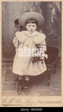 CDV victorienne (Carte de visite) montrant une jeune fille portant un beau manteau et un chapeau tout en maintenant sa poupée. Banque D'Images