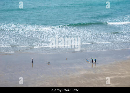 Femme chien walker et deux personnes avec des kayaks sur la plage à Traeth Llyfn, Pembrokeshire, Pays de Galles. Banque D'Images