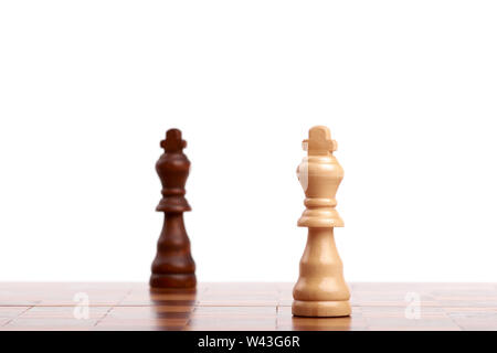 Deux pièces d'échecs en bois, le roi noir et blanc sur la carte. Stratégie et victoire isolé sur fond blanc. Banque D'Images