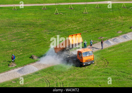 Saint Petersburg, Russie - Juin 20,2019 : Dump Truck KAMAZ verse de gravier sur un sentier piétonnier à la place publique. Les ouvriers travaillent avec des pelles. Banque D'Images