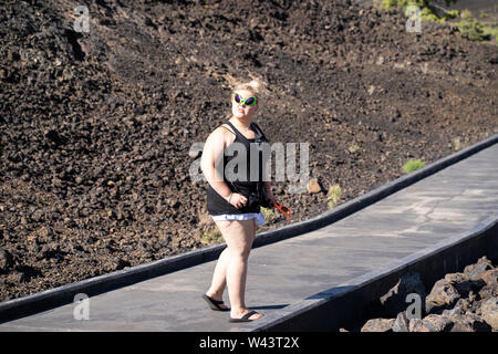 Blond woman wearing sunglasses exotiques marche sur un trottoir en cratères de la Lune Monument National en Idaho. Concept pour extraterrestrial Banque D'Images