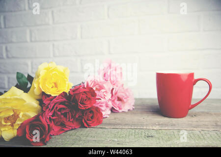 Tasse de café et de roses sur la table en bois sur mur de brique background Banque D'Images