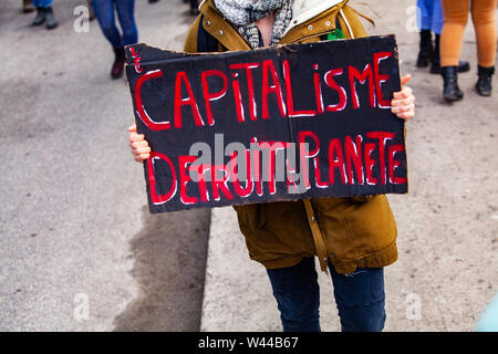 Une vue rapprochée d'un signe, le capitalisme français lecture détruit notre planète, tenu par un militant écologique lors d'une rue paisible de protestation. Banque D'Images