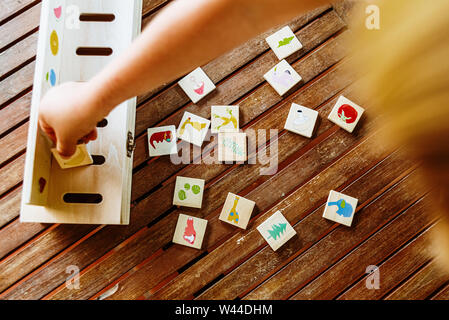 Mains d'un enfant à l'aide d'un jouet en bois pour comparer des images, utilisés dans les pédagogies alternatives, dans l'arrière-cour de sa maison. Banque D'Images