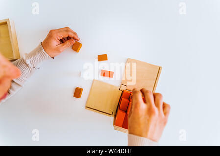 Les mains de l'enfant apprendre à mettre en place les pièces d'un puzzle en bois 3d. Banque D'Images