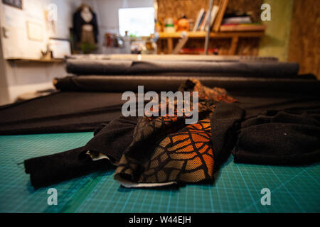 Orange et noir à motifs textiles, vu de près, sur l'établi à l'intérieur d'un atelier de mode. Rouleaux de prêt de matériel pour la couture. Banque D'Images