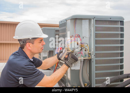Technicien CVC le câblage d'un condensateur de marche sur un climatiseur à condensation à l'extérieur. Banque D'Images