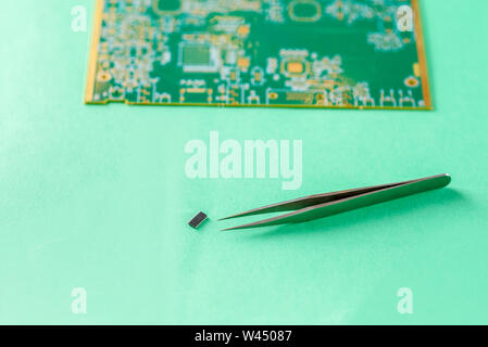 Brucelles, puce d'ordinateur et estompé petit CI-circuits imprimés sur fond vert. Le concept de l'ordinateur, le service, l'électronique, le matériel, repa Banque D'Images