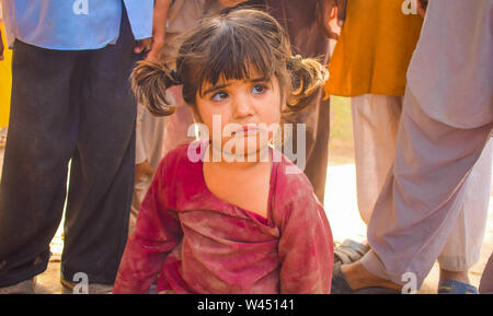 Punjab Pakistan-April,14,2019:close up d'une petite fille assise sur la terre,pleurs peu girle en robe rouge à la triste,triste et de mauvaise mo Banque D'Images