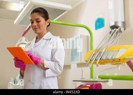 Femme dentiste concentré avec un comprimé orange permanent Banque D'Images