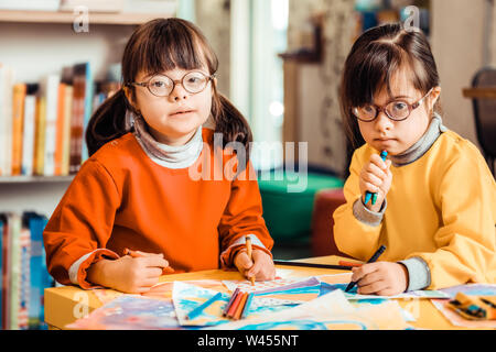 Deux jeunes filles aux cheveux noirs dans les lunettes et des sweat-shirts Banque D'Images