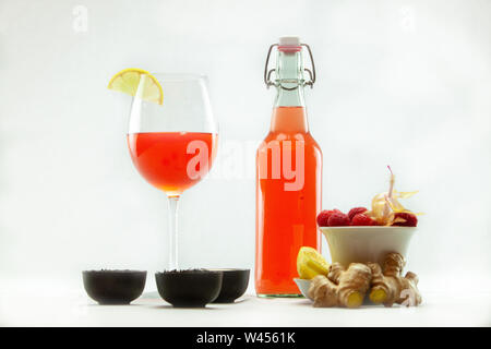 Désaltérant thé Kombucha est vu sur un fond blanc avec des ingrédients bruts. Boissons alcoolisées fruitées dans une bouteille sans étiquette et verre. Banque D'Images