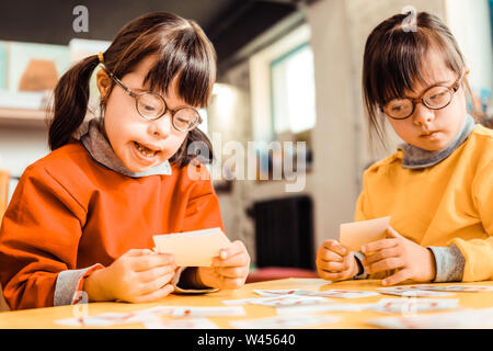 Smiling girl in eyeglasses sitting avec sa soeur grave Banque D'Images