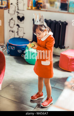 Petite fille pacifiques en robe orange vif portant la couronne en carton Banque D'Images
