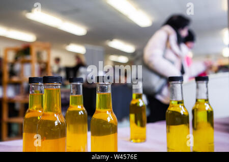 Une vue rapprochée sur les bouteilles d'huile d'olive à la maison sur un stand à une exposition de Noël, les personnes sont considérées brouillée derrière avec des prix pour la copie ci-dessus. Banque D'Images