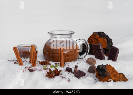 Ingrédients et un pichet de thé chai chaga sont vus dans la neige, un champignon épicé brew censées favoriser la santé du système immunitaire et détoxiquer le corps Banque D'Images