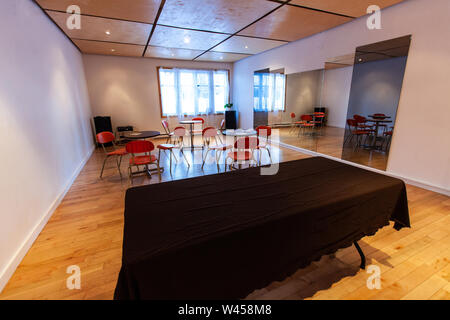 Une salle vide est perçue pour une fonction. Tables et fauteuils rouges sont vues par de grands miroirs à l'intérieur d'un bâtiment communal, avec copie espace à l'avant-plan. Banque D'Images