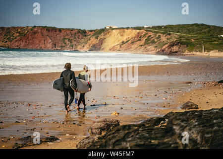 Deux surfers carrying leurs conseils le long d'une plage Banque D'Images