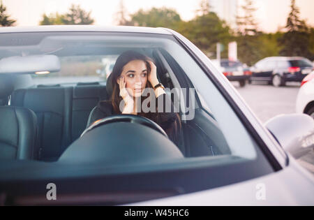 La jeune fille dans la voiture est dans un embouteillage. Banque D'Images