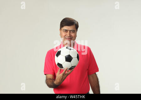 Portrait d'un homme tenant un ballon de soccer et souriant Banque D'Images