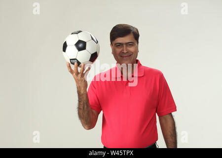 Portrait d'un homme tenant un ballon de soccer et souriant Banque D'Images